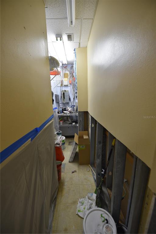 A narrow utility room features exposed wall studs, scattered supplies, and a cluttered server rack — 5124 US HIGHWAY 19, NEW PORT RICHEY, FL