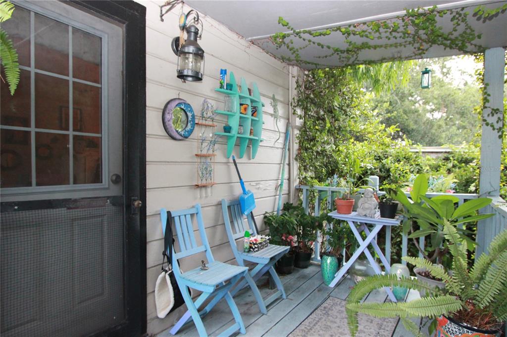 A covered porch features light blue wooden chairs, a matching shelf, and various potted plants — 415 E GORE STREET, ORLANDO, FL