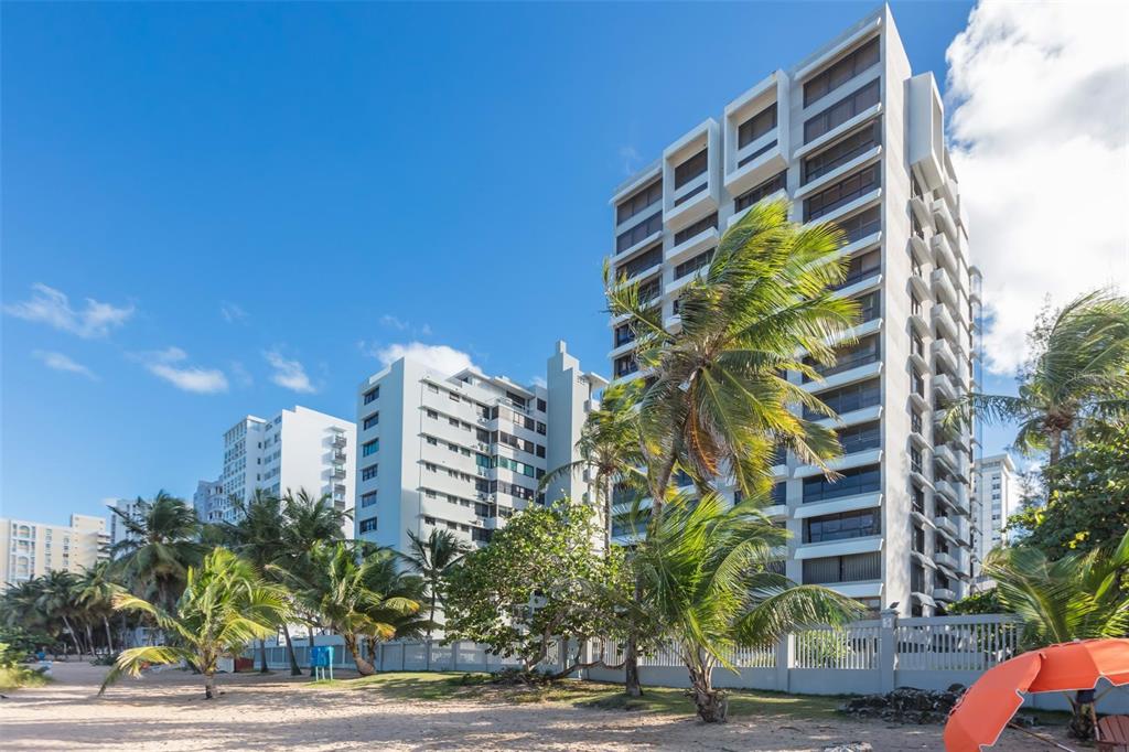 A view of tall beachfront apartment buildings with palm trees on a sandy beach — 1507 ASHFORD AVENUE UNIT 1201, SAN JUAN, PR