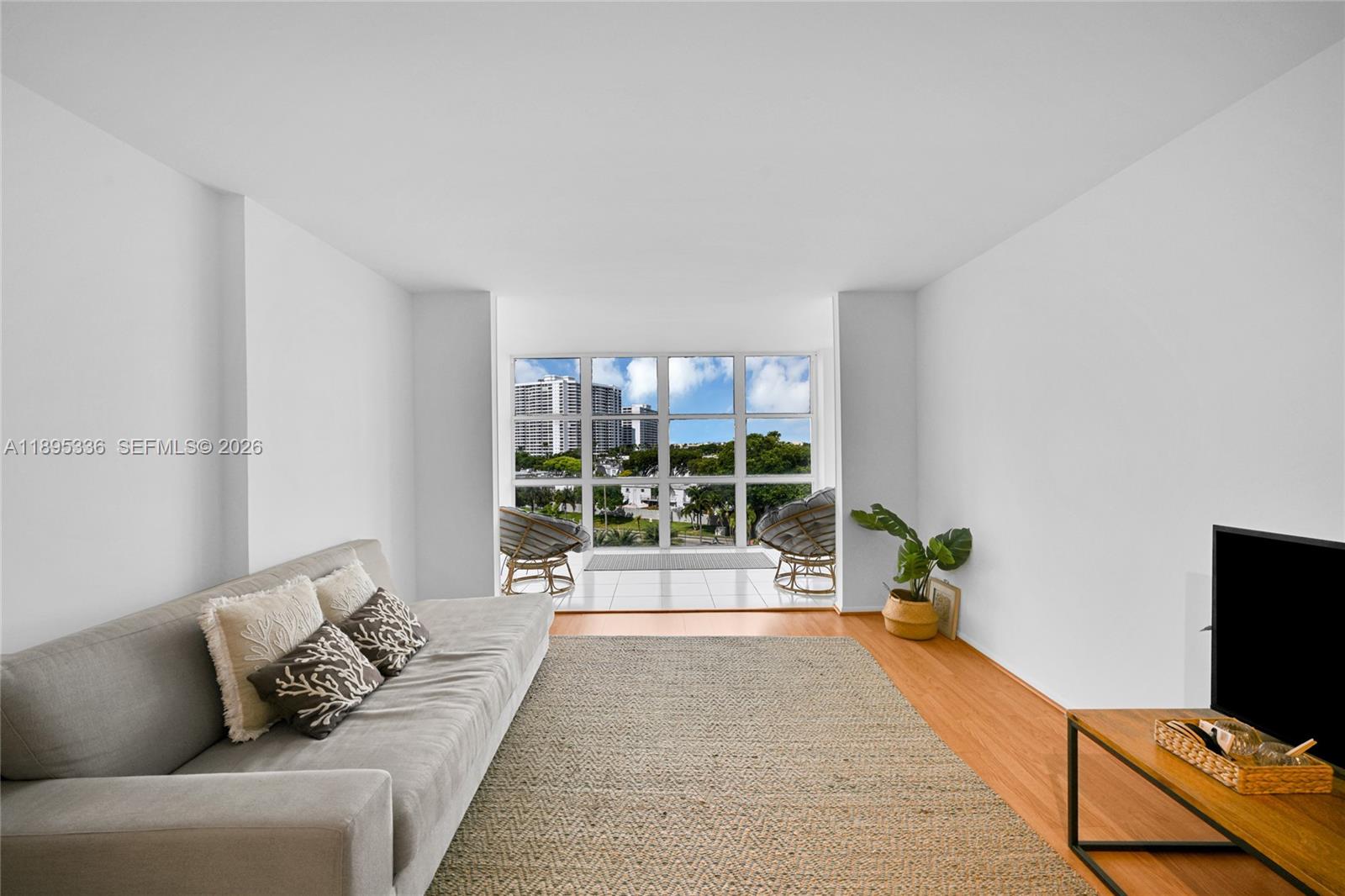 A living room features a gray sofa, a jute rug, and floor-to-ceiling windows with views — 800 Parkview Dr # 605, Hallandale Beach FL 33009, HALLANDALE BEACH, FL