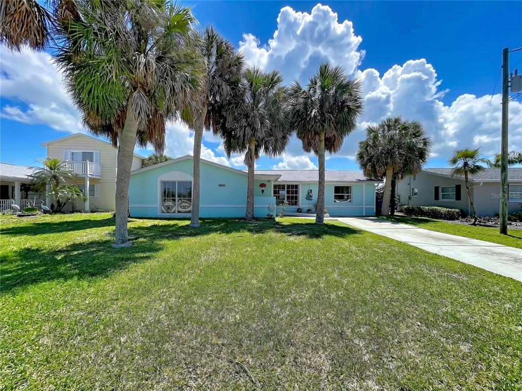 A light blue single-story house with a concrete driveway and several palm trees in front — 4930 BAY PARK DRIVE, PORT RICHEY, FL