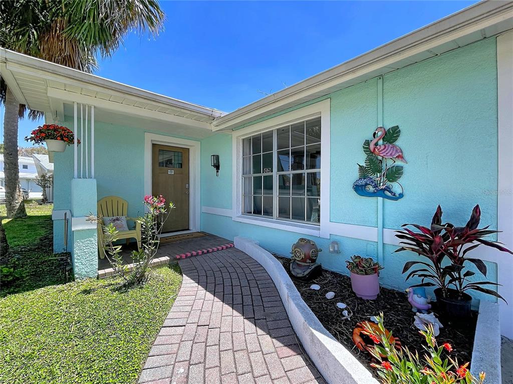 A light blue house exterior features a brick walkway leading to a wooden front door — 4930 BAY PARK DRIVE, PORT RICHEY, FL