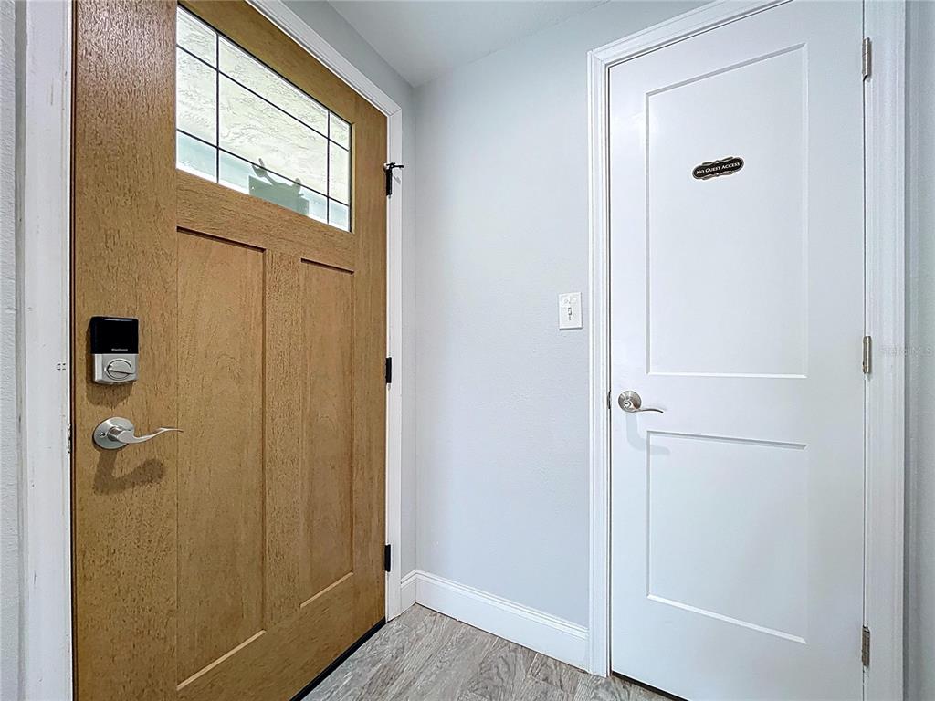 An entryway features a wood-paneled front door, a white interior door, and light-colored flooring — 4930 BAY PARK DRIVE, PORT RICHEY, FL