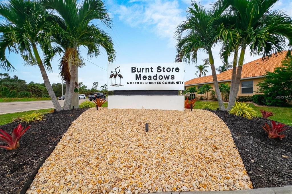 A sign for Burnt Store Meadows stands in a landscaped bed with palm trees — 7353 N SEAGRAPE ROAD, PUNTA GORDA, FL