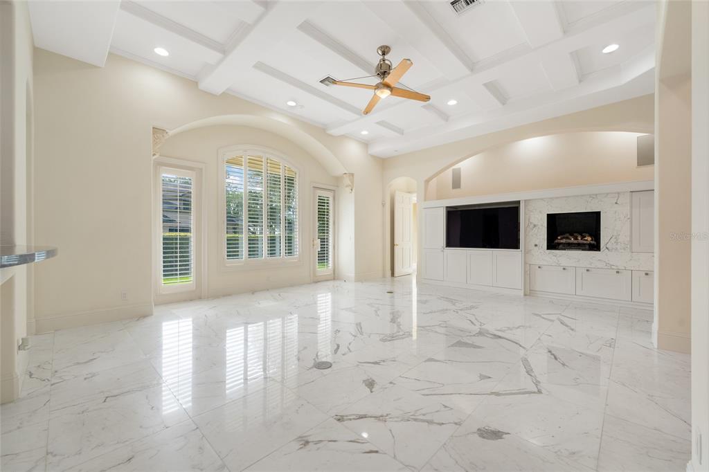 A spacious living room features white marble floors, a coffered ceiling, and a built-in fireplace — 9701 LAKE ISLEWORTH COURT, WINDERMERE, FL