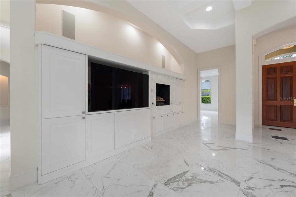A living room features white built-in cabinetry, a television, a fireplace, and marble flooring — 9701 LAKE ISLEWORTH COURT, WINDERMERE, FL