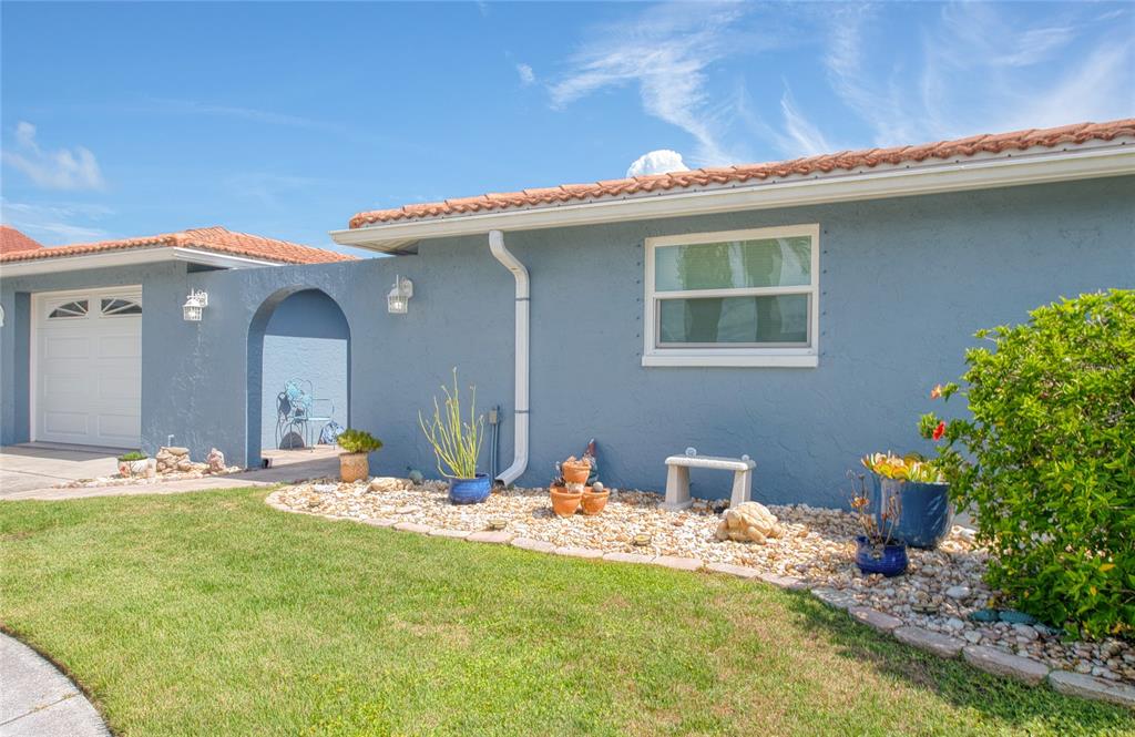A blue stucco house exterior features a tiled roof, a garage, and a landscaped yard — 7039 SOUTHWIND DRIVE, HUDSON, FL