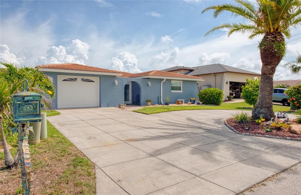 A blue single-story house with a tile roof, a garage, and a palm tree — 7039 SOUTHWIND DRIVE, HUDSON, FL