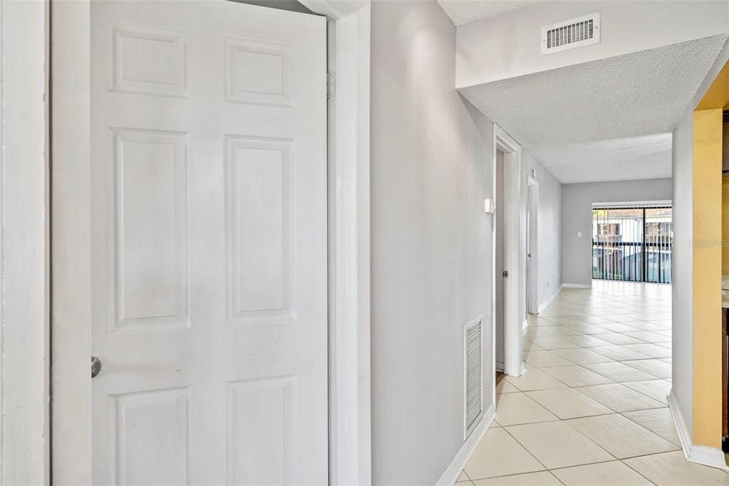 A white door opens into a hallway with light-colored tile flooring leading toward a window — 1918 PELICAN LANDING BOULEVARD UNIT 1125, CLEARWATER, FL
