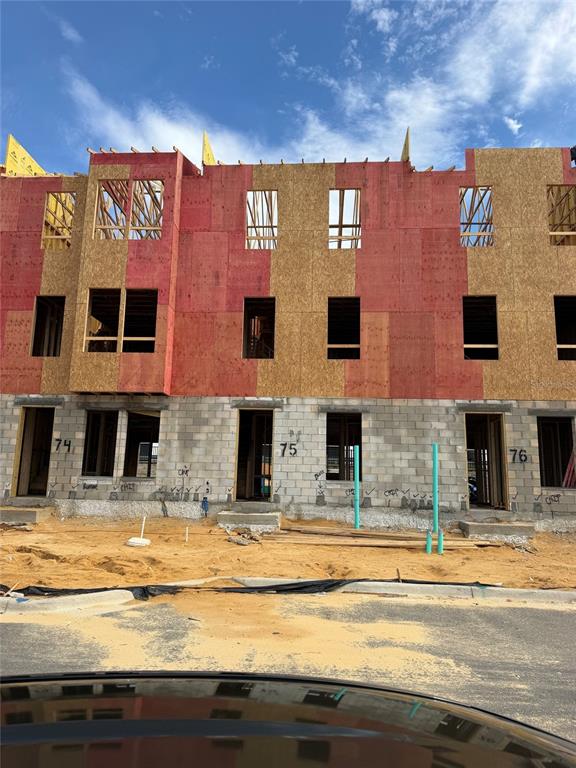 A three-story townhouse under construction with concrete block lower walls and wood-sheathed upper levels — 15165 GROVESIDE ROAD, WINTER GARDEN, FL