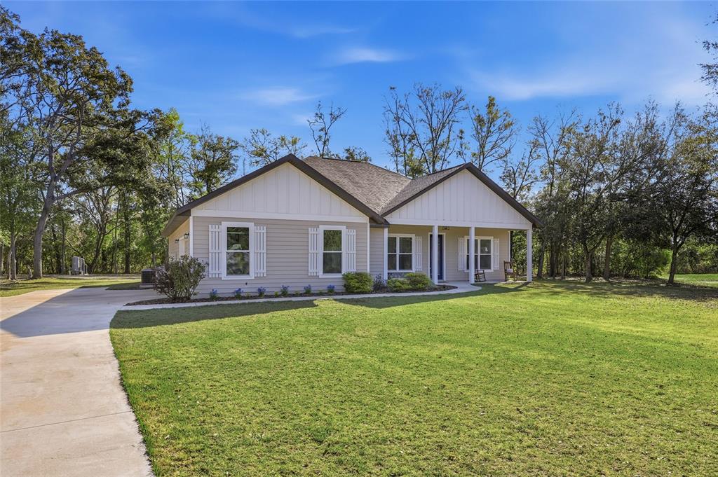 A single-story house with light-colored siding and a covered front porch sits on a lawn — 8920 NE 8TH PLACE, HIGH SPRINGS, FL