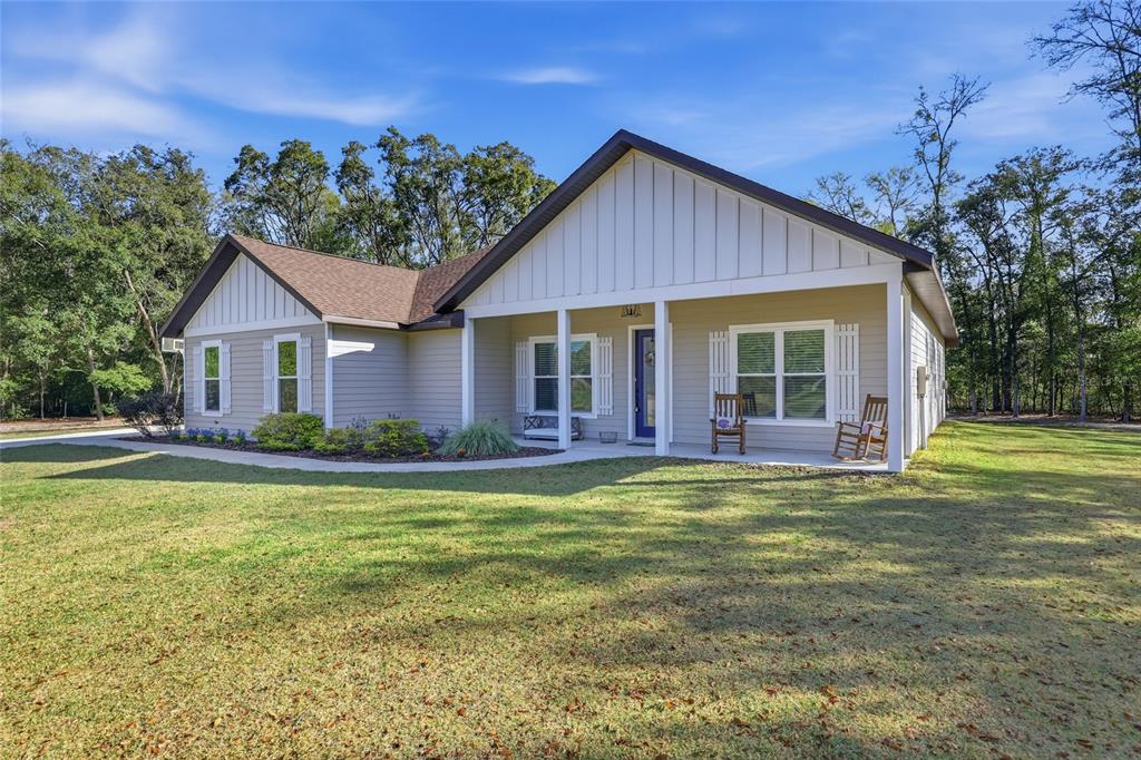 A single-story house with light-colored siding and a covered front porch sits on a lawn — 8920 NE 8TH PLACE, HIGH SPRINGS, FL