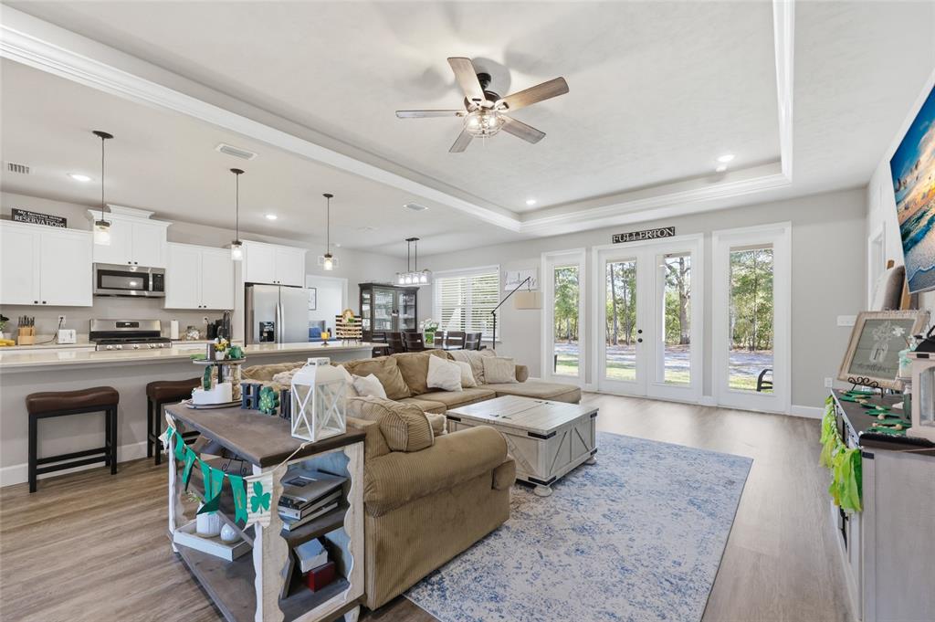An open-concept living room and kitchen featuring white cabinetry, a sectional sofa, and glass doors — 8920 NE 8TH PLACE, HIGH SPRINGS, FL