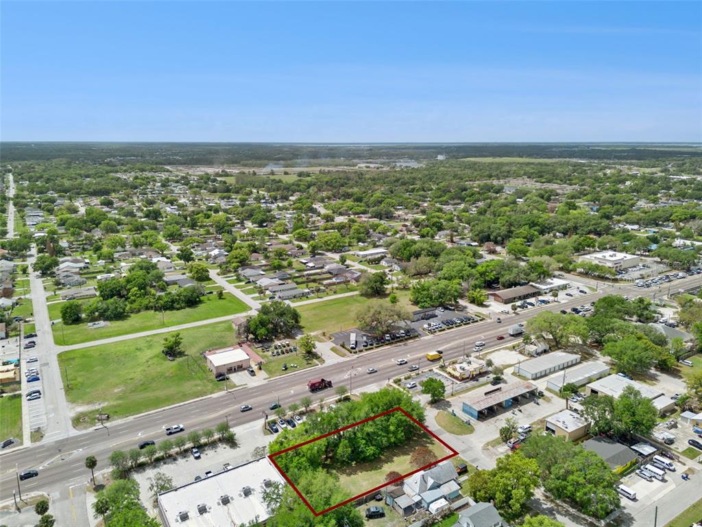 An aerial view shows a rectangular vacant lot outlined in red near a busy road — 1215 WISCONSIN AVENUE, ST CLOUD, FL