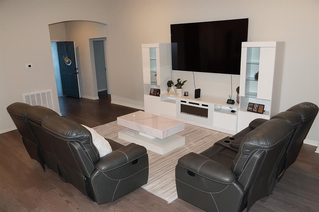 A living room features dark leather reclining sofas, a white entertainment center, and a coffee table — 621 VITTORIO DRIVE, WINTER HAVEN, FL
