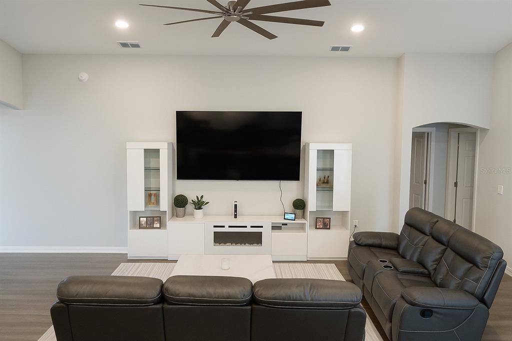 A living room features a large wall-mounted television above a white media console and fireplace — 621 VITTORIO DRIVE, WINTER HAVEN, FL