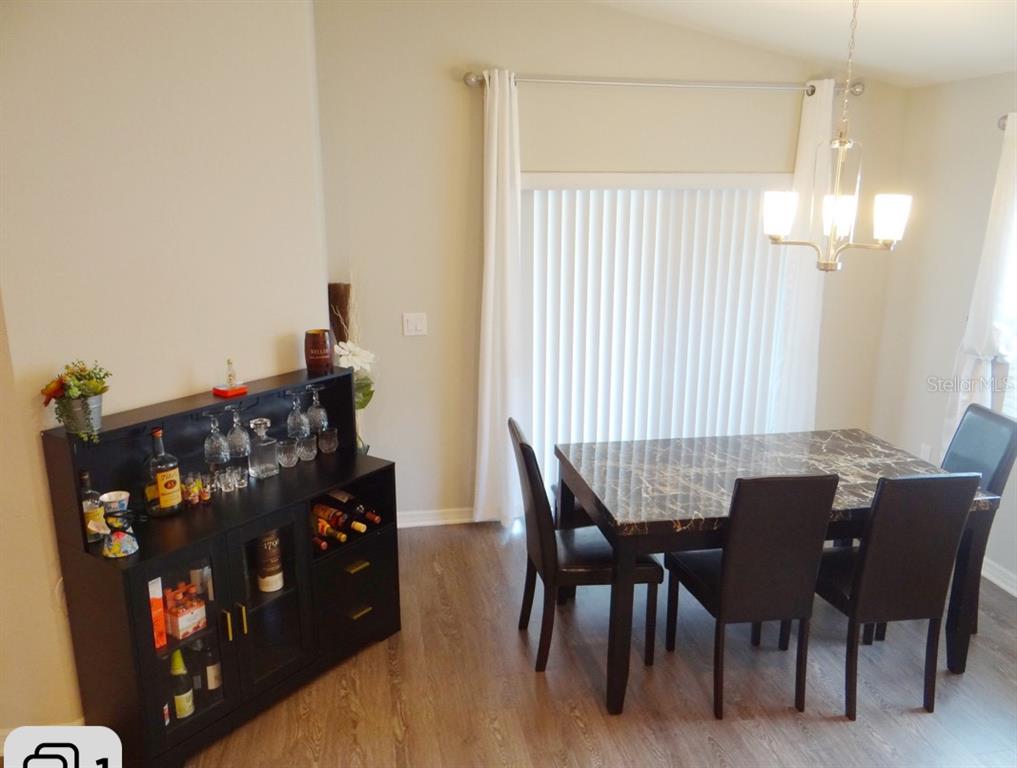 A dining room features a dark wood bar cabinet, a marble-topped table, and sliding glass doors — 621 VITTORIO DRIVE, WINTER HAVEN, FL