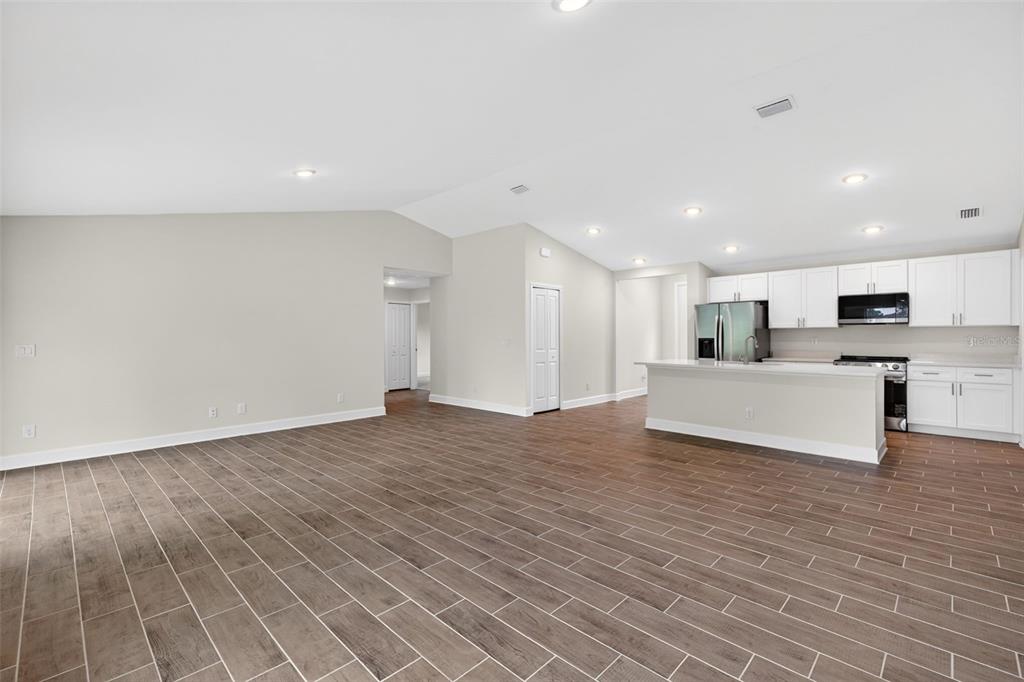 A modern kitchen features white cabinetry, a central island, and wood-look tile flooring — 23447 BEATRICE AVENUE, PORT CHARLOTTE, FL