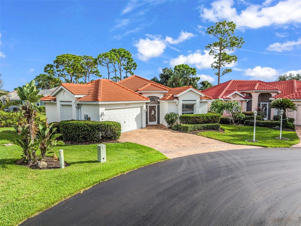 A single-story house with a terracotta tile roof, white stucco walls, and a paved driveway — 4029 CAPE COLE BOULEVARD, PUNTA GORDA, FL