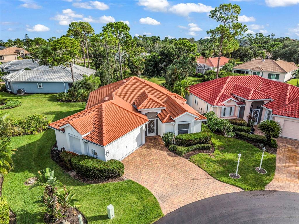 An aerial view shows a single-story house with a red tile roof and brick driveway — 4029 CAPE COLE BOULEVARD, PUNTA GORDA, FL