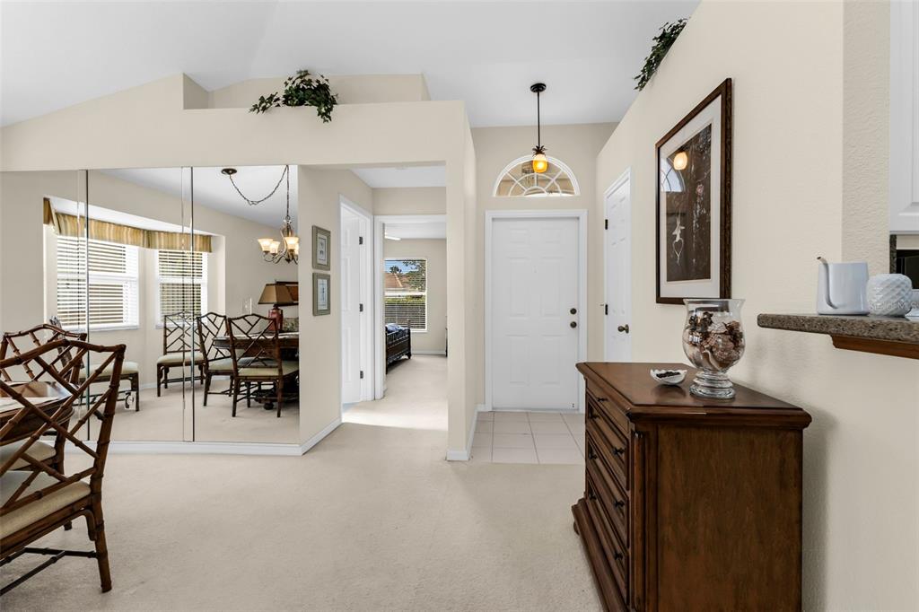 A dining area with a mirrored wall leads to an entryway with a white door — 4029 CAPE COLE BOULEVARD, PUNTA GORDA, FL