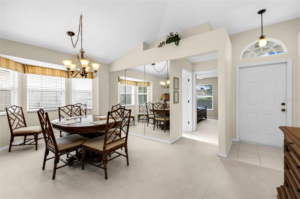 A dining area with a round table, rattan chairs, mirrored wall, and adjacent entryway — 4029 CAPE COLE BOULEVARD, PUNTA GORDA, FL