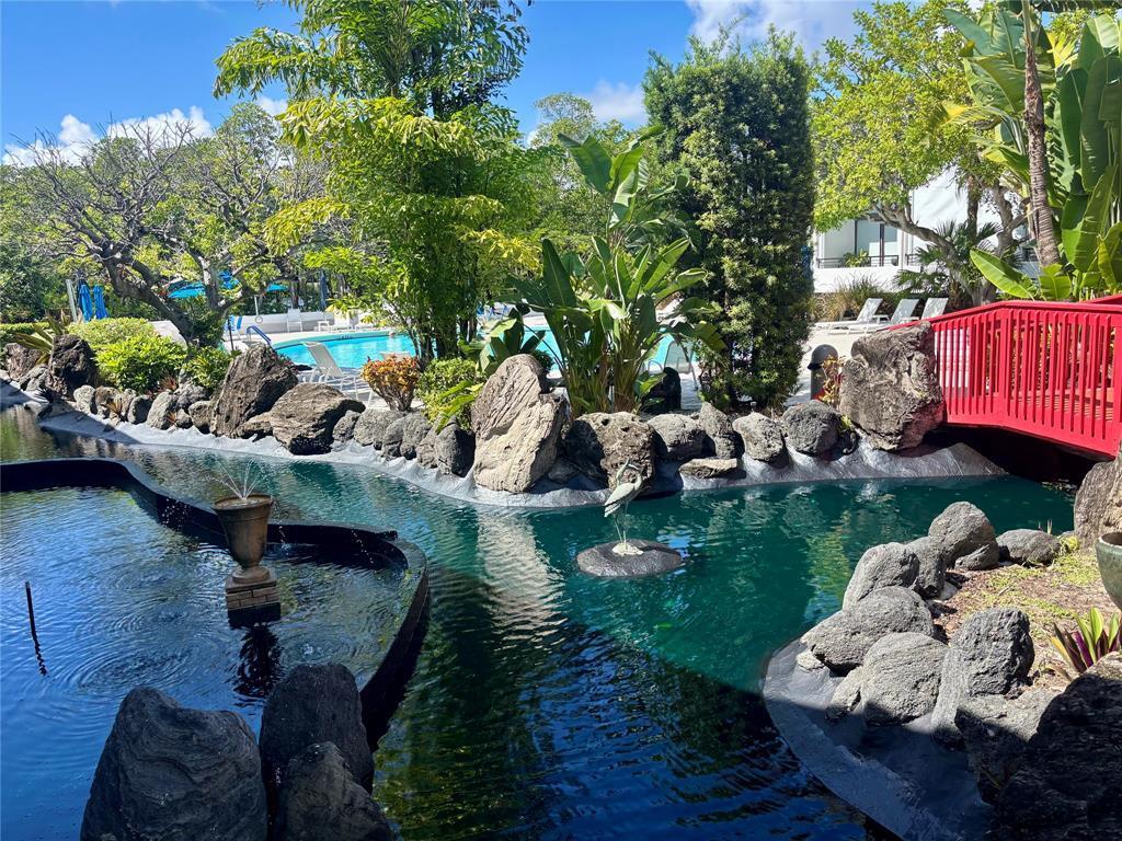 A red bridge crosses a pond with a fountain and rock landscaping near a pool — 3589 S Ocean Boulevard # 10, South Palm Beach FL 33480, SOUTH PALM BEACH, FL