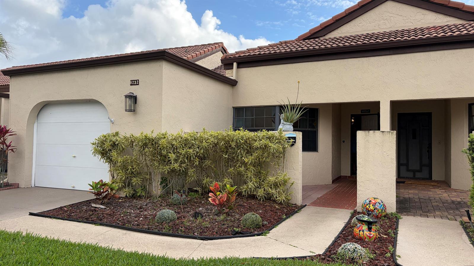 A single-story stucco house features a garage, a front entryway, and a landscaped front yard — 8232 Waterline Drive, Boynton Beach FL 33472, BOYNTON BEACH, FL