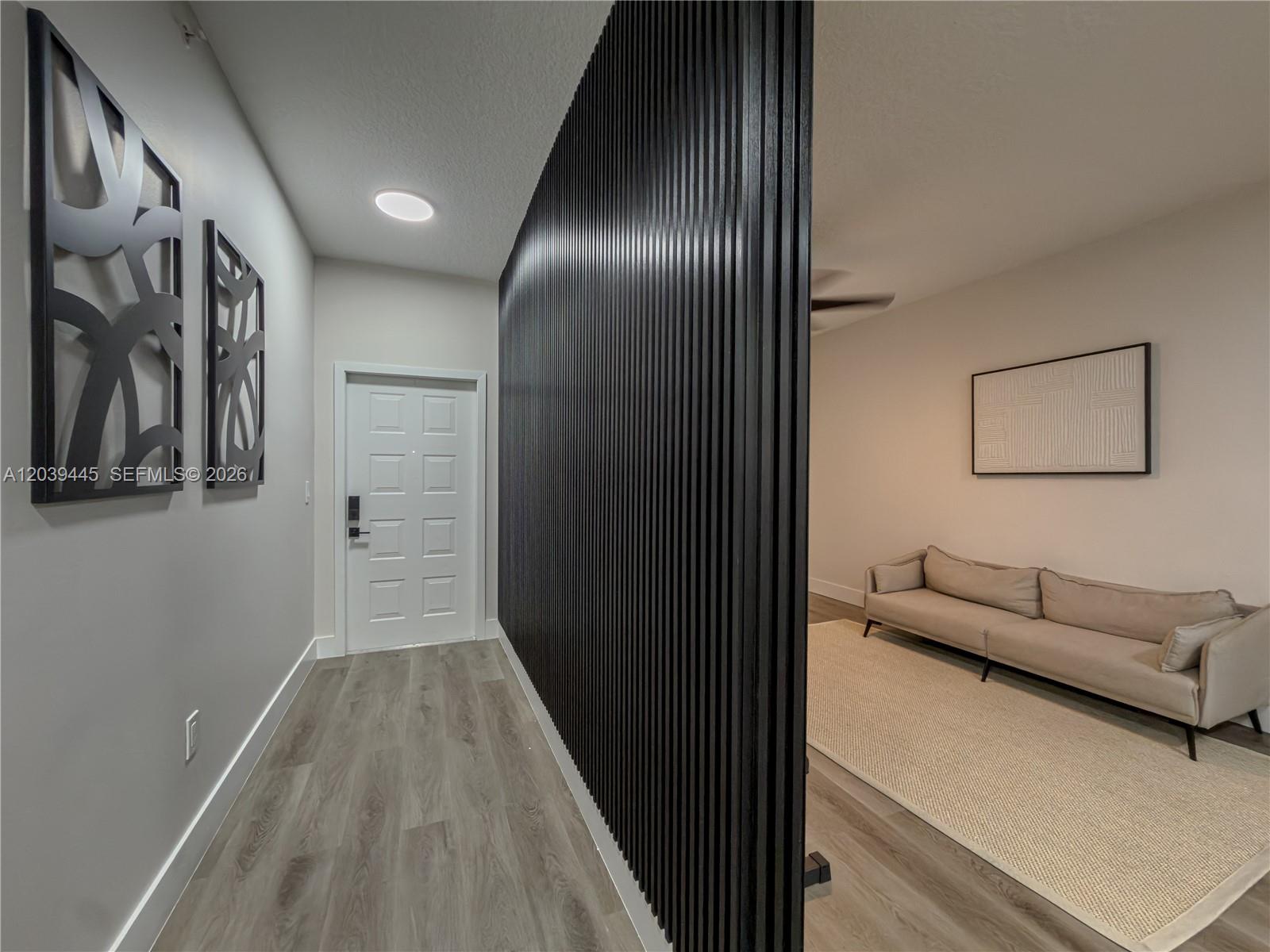A hallway with a black slatted accent wall leads to a living area with a sofa — 10750 NW 66th St # 504, Doral FL 33178, DORAL, FL