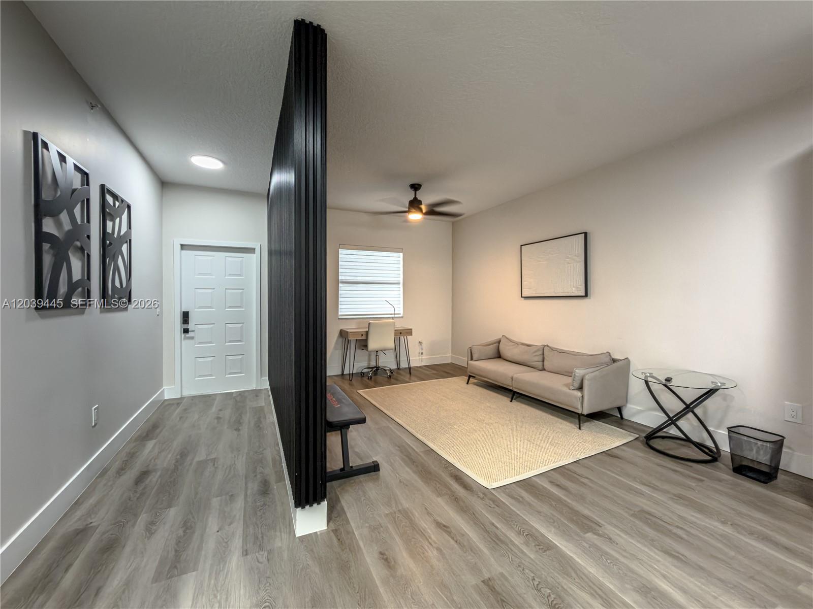 A living room features a black slat room divider, light wood flooring, and a beige sofa — 10750 NW 66th St # 504, Doral FL 33178, DORAL, FL