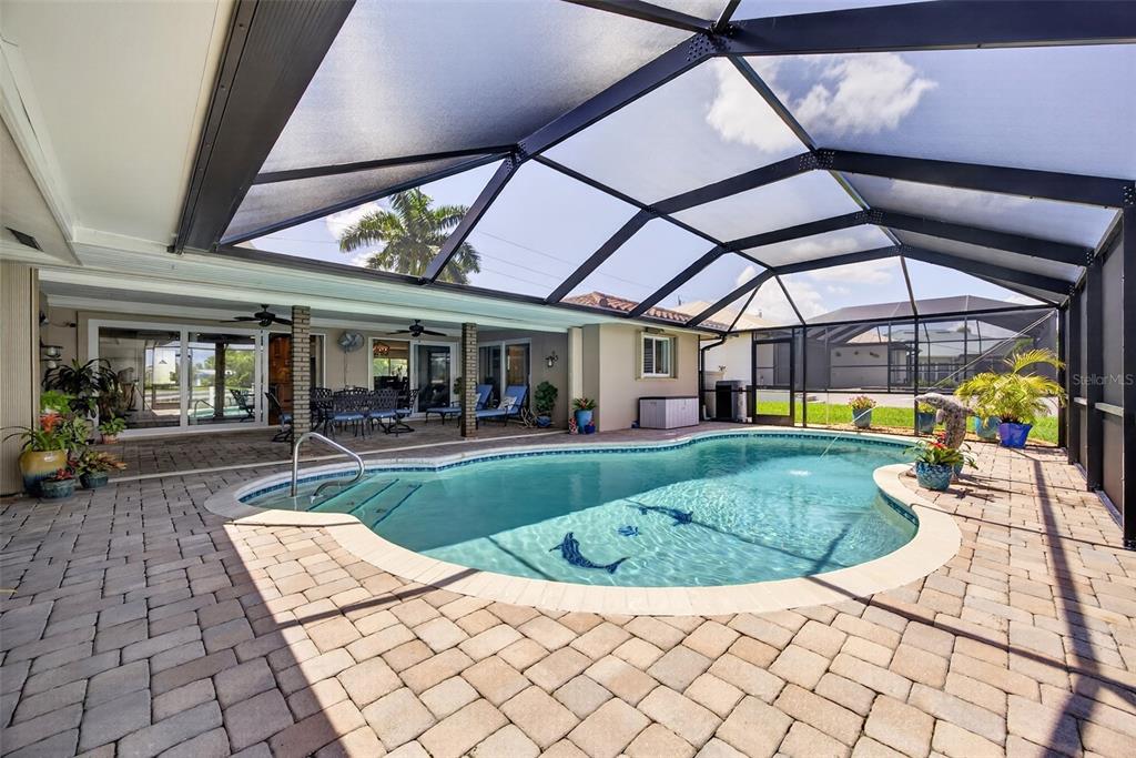 A screened-in patio features a swimming pool with dolphin mosaics and brick paver flooring — 359 BAL HARBOR BOULEVARD, PUNTA GORDA, FL