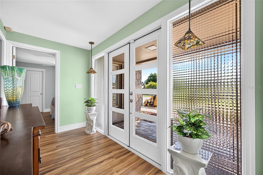 An entryway features wood-look flooring, light green walls, a double glass door, and pendant lighting — 359 BAL HARBOR BOULEVARD, PUNTA GORDA, FL