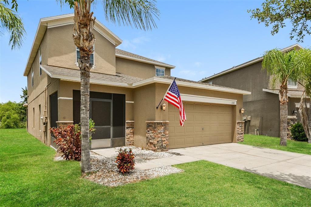 A two-story tan house with a stone-accented garage and a screened-in front entryway — 2114 RICHWOOD PIKE DRIVE, RUSKIN, FL