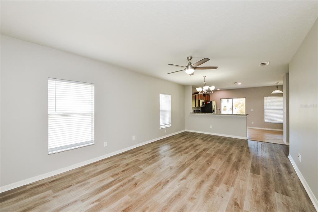An open-concept living area with light gray walls, wood-look flooring, and a kitchen beyond — 2114 RICHWOOD PIKE DRIVE, RUSKIN, FL