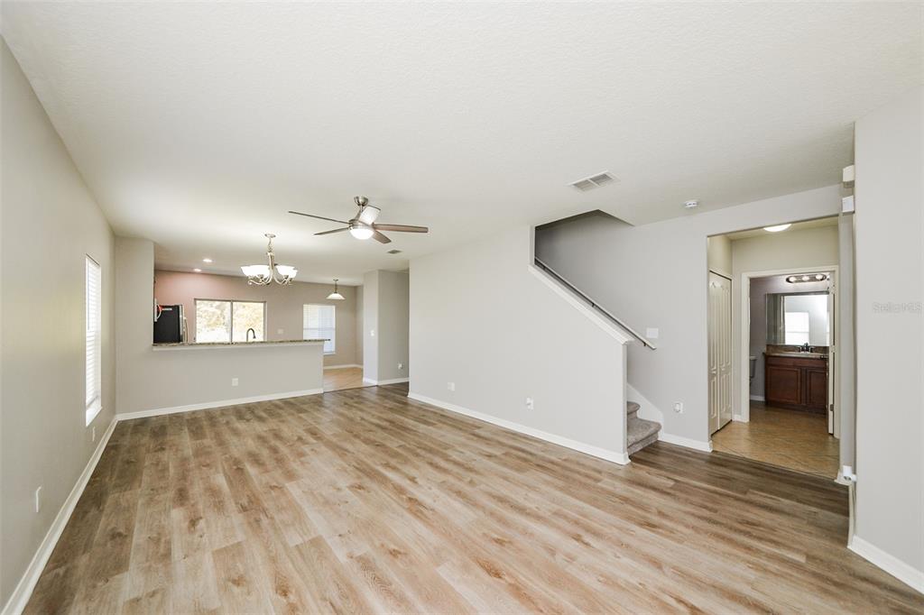 An open-concept living area features wood-look flooring, a staircase, and a view into the kitchen — 2114 RICHWOOD PIKE DRIVE, RUSKIN, FL
