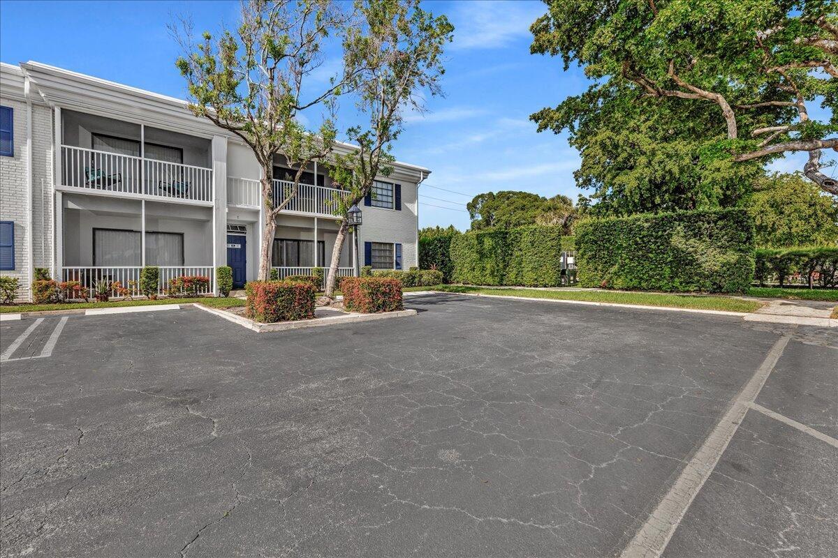A two-story white apartment building with screened balconies sits behind a paved parking lot — 180 Cypress Club Drive # 816, Pompano Beach FL 33060, POMPANO BEACH, FL