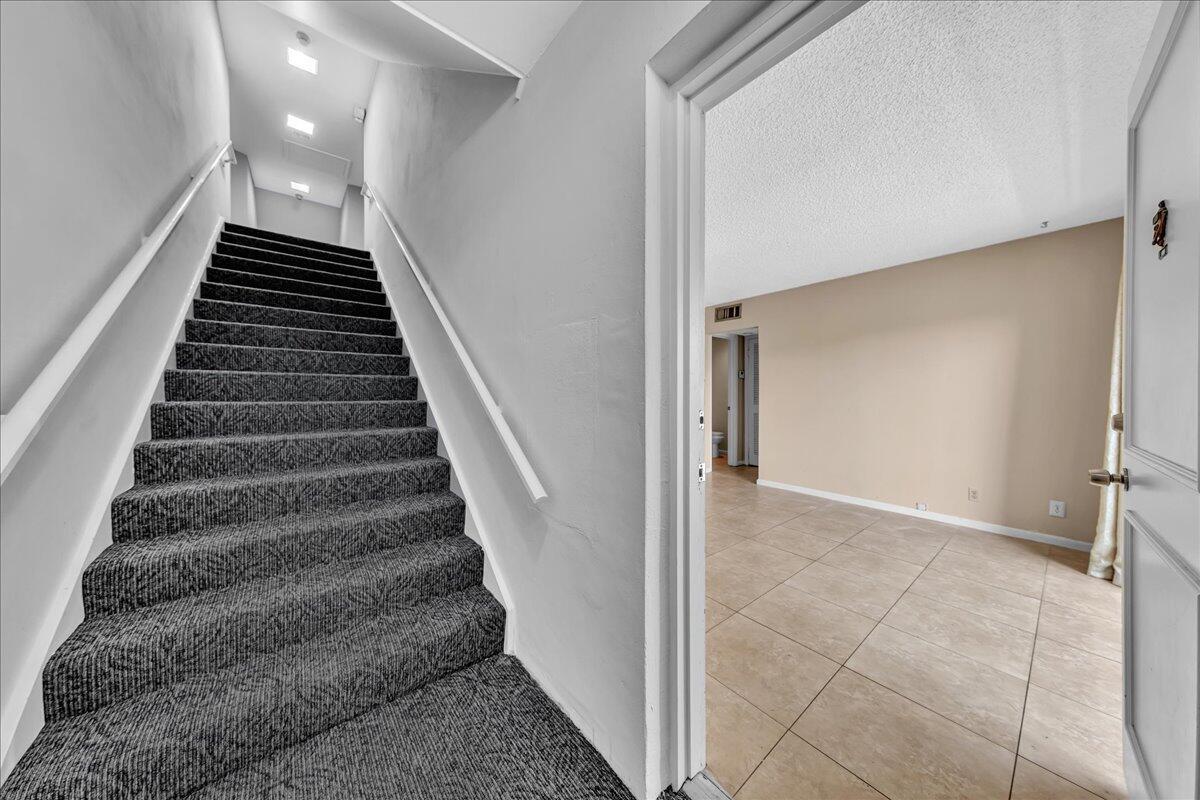 A carpeted staircase leads upward next to a doorway opening into a tiled room — 180 Cypress Club Drive # 816, Pompano Beach FL 33060, POMPANO BEACH, FL