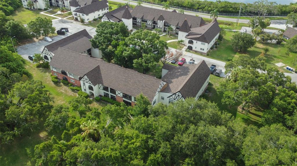 An aerial view of a multi-story apartment complex with Tudor-style architecture and surrounding trees — 420 N BAYSHORE BOULEVARD UNIT 102, CLEARWATER, FL