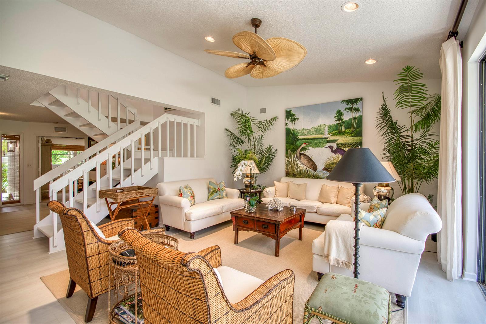 A living room features white sofas, wicker armchairs, a wooden coffee table, and a staircase — 525 Prestwick Circle, Palm Beach Gardens FL 33418, PALM BEACH GARDENS, FL