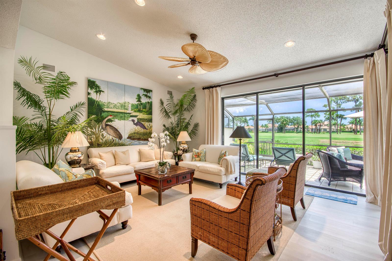 A living room features white sofas, wicker armchairs, a coffee table, and large sliding glass doors — 525 Prestwick Circle, Palm Beach Gardens FL 33418, PALM BEACH GARDENS, FL