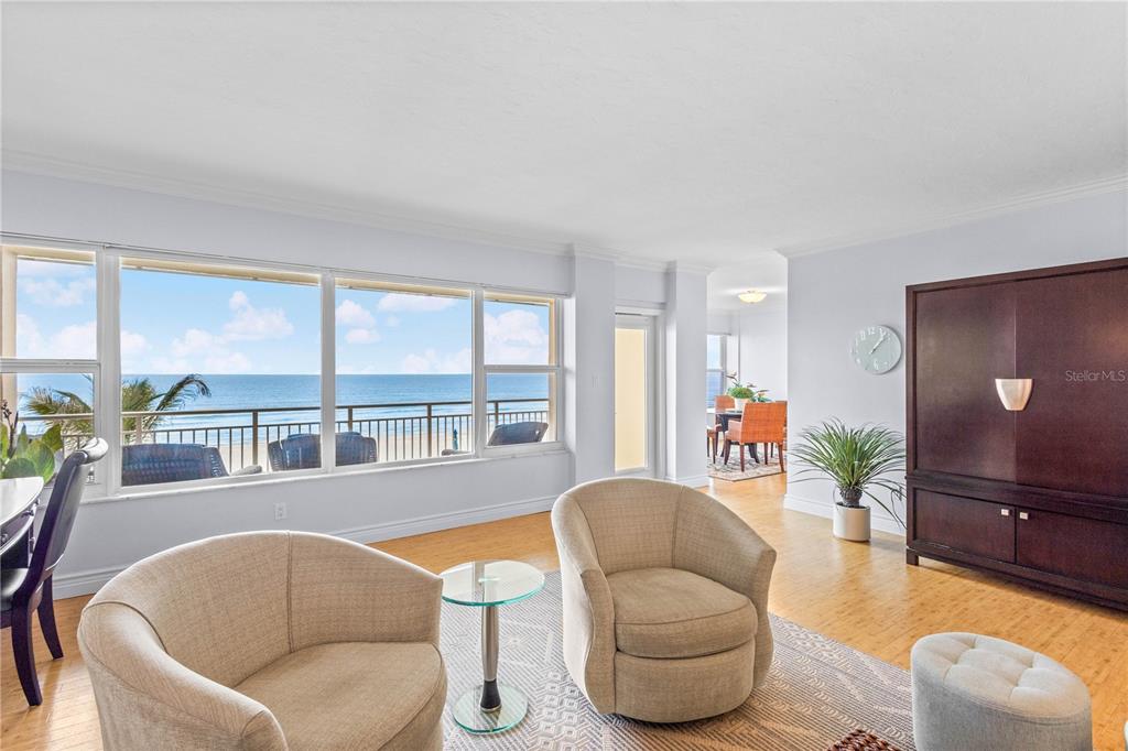 A living room with light wood floors, two beige armchairs, and a view of the ocean — 603 LONGBOAT CLUB ROAD UNIT 202N, LONGBOAT KEY, FL