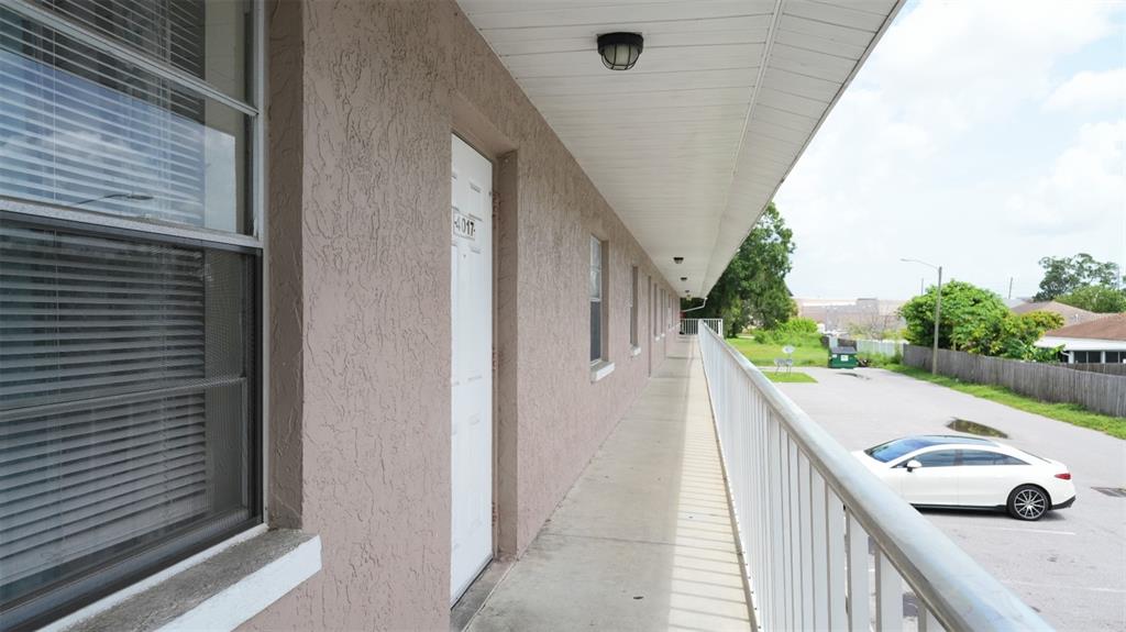 An exterior walkway with a metal railing overlooks a parking lot and a residential street — 4015 76TH AVENUE N UNIT 4025, PINELLAS PARK, FL