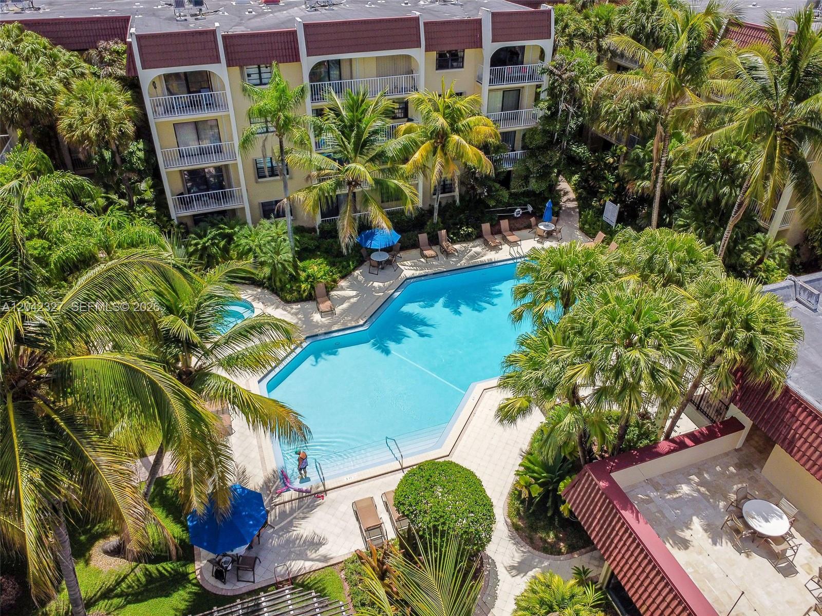 An aerial view shows a swimming pool surrounded by palm trees and apartment buildings — 9301 SW 92nd Ave # A302, Miami FL 33176, MIAMI, FL