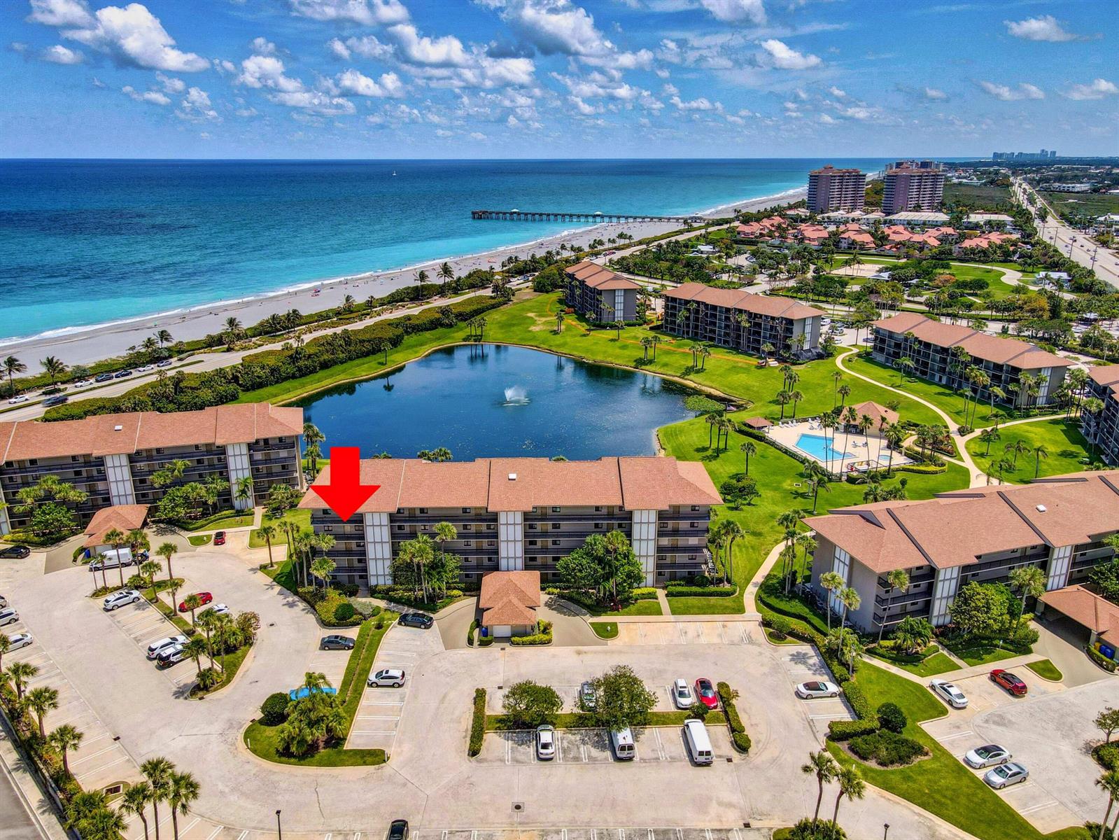 An aerial view shows a multi-story residential building with a red arrow pointing toward it — 201 S Seas Drive # 401, Jupiter FL 33477, JUPITER, FL