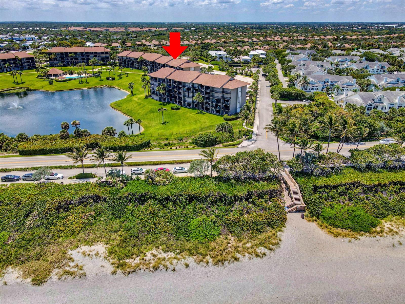 An aerial view shows a multi-story apartment building near a lake and the beach — 201 S Seas Drive # 401, Jupiter FL 33477, JUPITER, FL