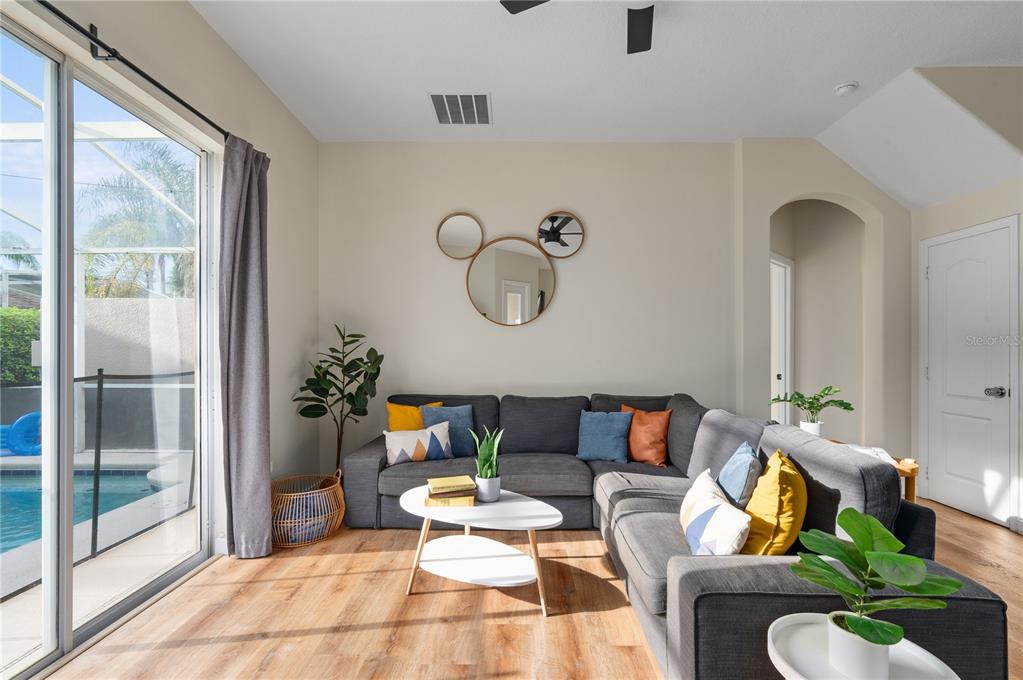 A living room features a gray sectional sofa, a white coffee table, and sliding glass doors — 740 BRUNELLO DRIVE, DAVENPORT, FL