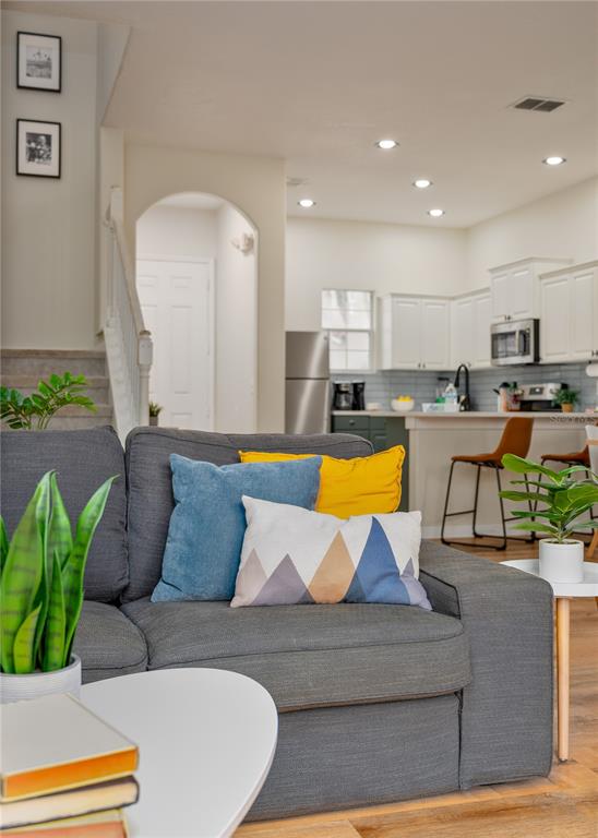A living room with a gray sofa faces an open kitchen with white cabinets — 740 BRUNELLO DRIVE, DAVENPORT, FL