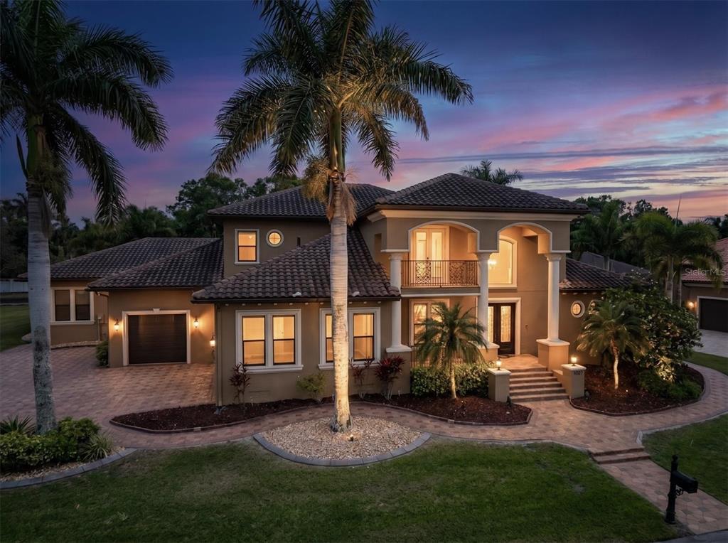 A two-story stucco house with a tiled roof, palm trees, and a paved driveway at dusk — 1067 ASHLAND AVENUE, TARPON SPRINGS, FL