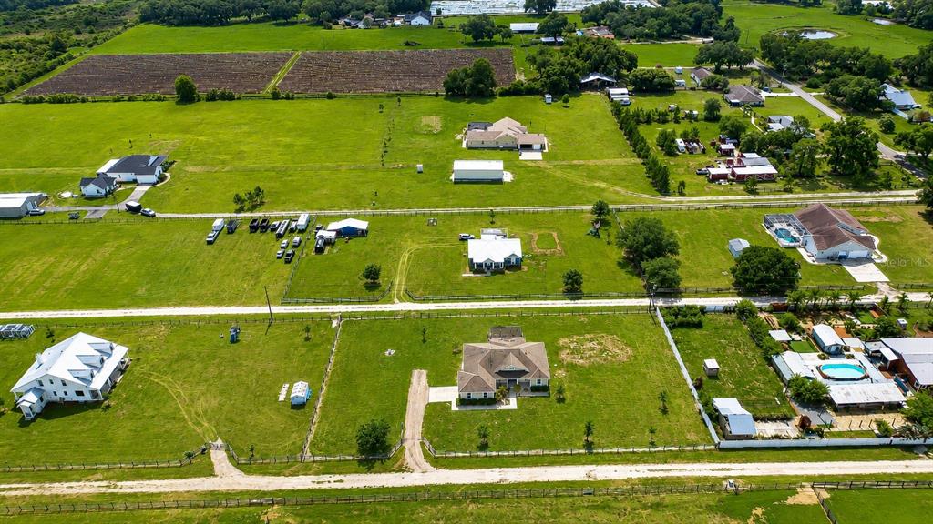An aerial view shows several houses with outbuildings and fenced pastures in a rural landscape — 4008 MCINTOSH ESTATES LANE, PLANT CITY, FL