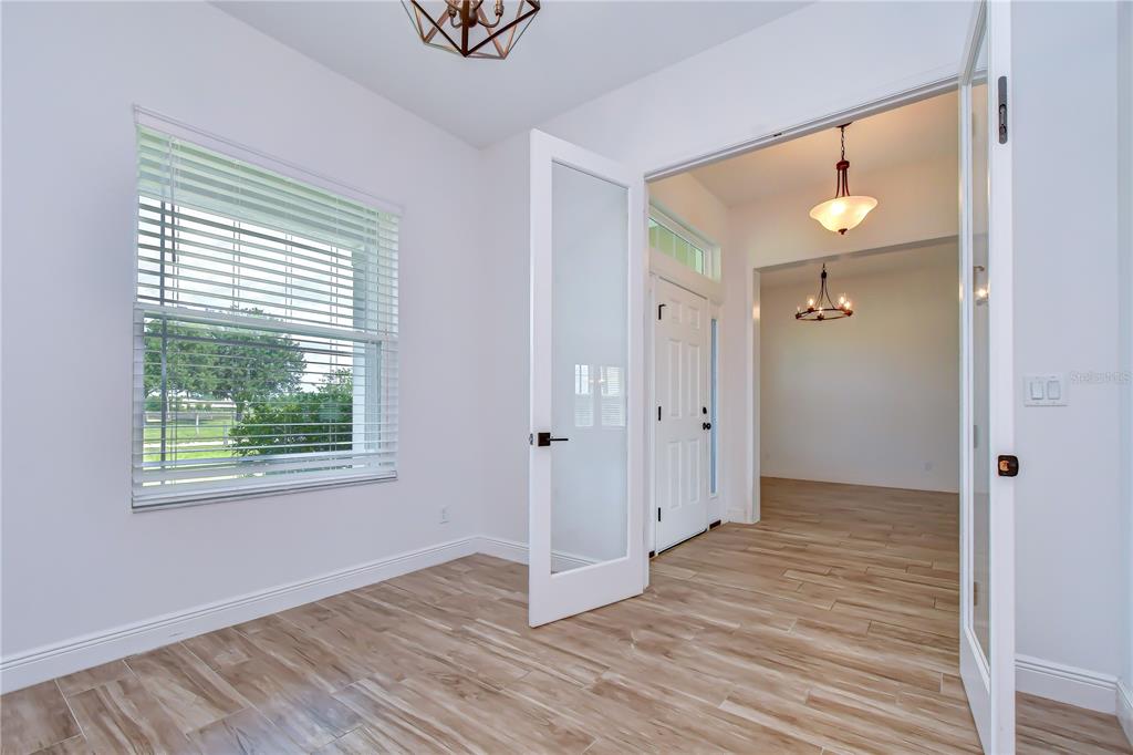 A room with wood-look tile flooring and French doors opening to an entryway — 4008 MCINTOSH ESTATES LANE, PLANT CITY, FL